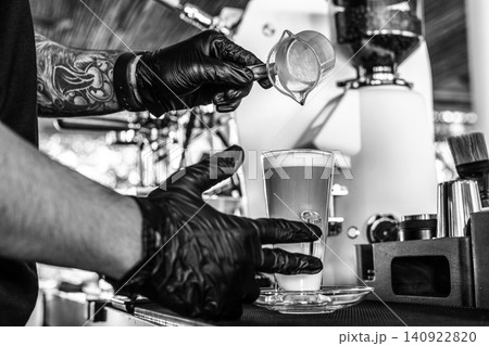 Barista at premium coffee shop preparing a Latte with professional equipment in Black & White Barista at premium coffee shop preparing a Latte with professional equipment in Black & White 140922820