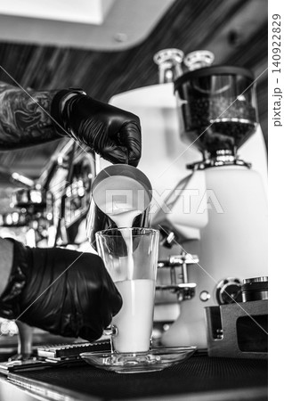 Barista at premium coffee shop preparing a Latte with professional equipment in Black & White Barista at premium coffee shop preparing a Latte with professional equipment in Black & White 140922829