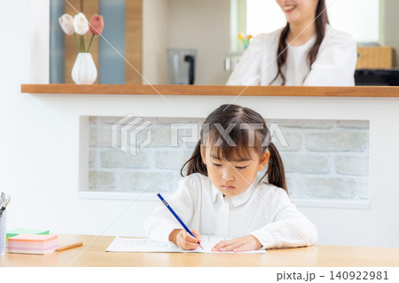 リビングで勉強をする子どもと見守る母 リビングで勉強をする子どもと見守る母 140922981