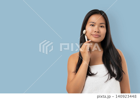 Woman uses facial tool for skin care in a spa room Woman uses facial tool for skin care in a spa room 140923448
