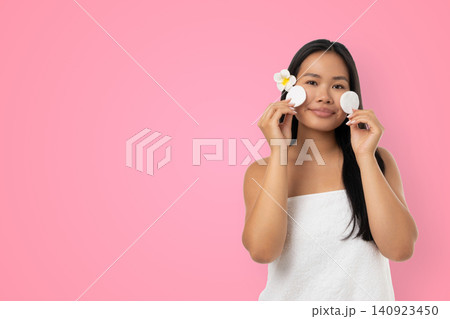 Woman enjoys skincare routine holding items in hands Woman enjoys skincare routine holding items in hands 140923450