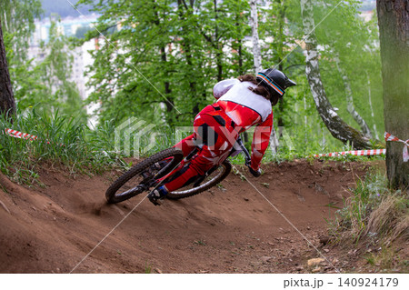 Rear view woman downhill racer riding Rear view woman downhill racer riding 140924179