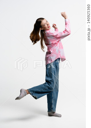 Cheerful teenage girl balancing on one leg and smiling at camera. Cheerful teenage girl balancing on one leg and smiling at camera. 140925360