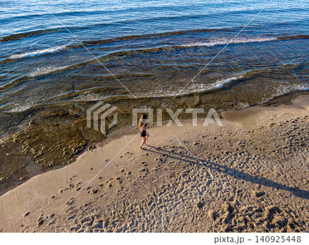 Young Woman Jogging on Sandy Beach at Sunrise along Sea Young Woman Jogging on Sandy Beach at Sunrise along Sea 140925448
