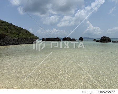 澄み渡る遠浅の海と黒い岩礁の風景 140925977