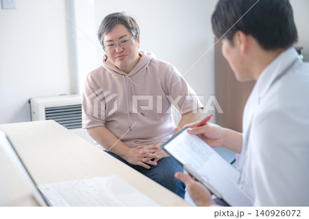 診察室で医師に相談する中年男性 診察室で医師に相談する中年男性 140926072