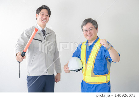 誘導棒とヘルメットを持つ笑顔の作業員 誘導棒とヘルメットを持つ笑顔の作業員 140926073