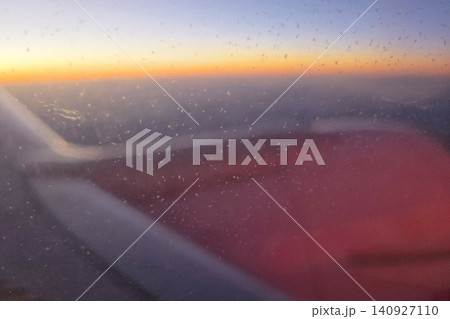 Sunrise over the horizon viewed from an airplane window while flying at high altitude during early morning hours Sunrise over the horizon viewed from an airplane window while flying at high altitude during early morning hours 140927110