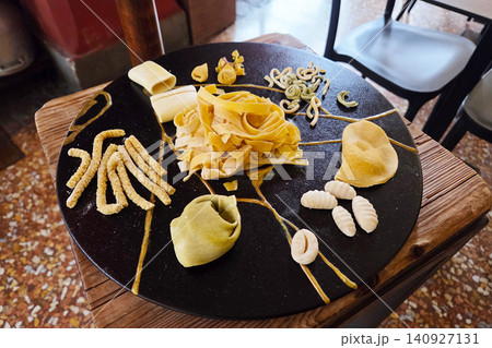 Unique pasta presentation on a black plate at a restaurant in Italy during lunch with various shapes and colors Unique pasta presentation on a black plate at a restaurant in Italy during lunch with various shapes and colors 140927131