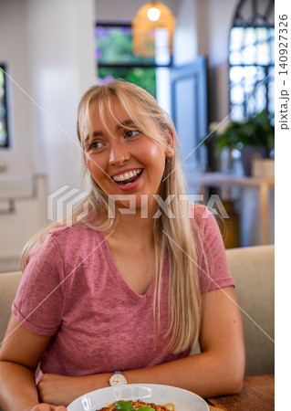 Woman sitting at cafe table smiling and looking left beside bowl of spaghetti Woman sitting at cafe table smiling and looking left beside bowl of spaghetti 140927326
