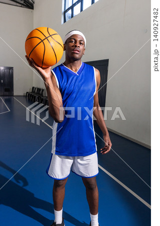 Adult african american basketball player wearing blue jersey standing on court with basketball 140927482