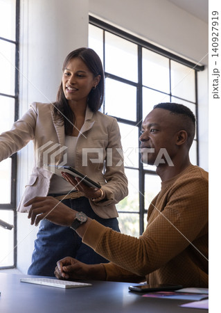 Diverse coworkers working at desk in office, using tablet, smartphone and wireless keyboard Diverse coworkers working at desk in office, using tablet, smartphone and wireless keyboard 140927919