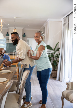 African American family preparing meal in modern kitchen at wooden dining table with covered dish African American family preparing meal in modern kitchen at wooden dining table with covered dish 140928021