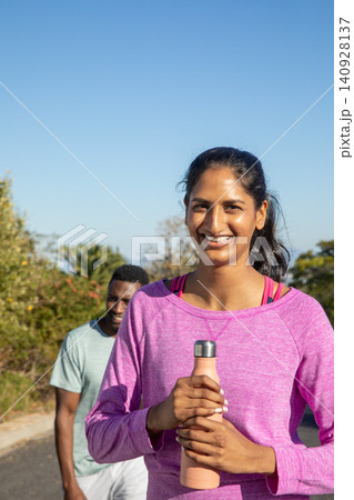 Diverse friends jogging on trail, indian woman in pink with peach water bottle, copy space Diverse friends jogging on trail, indian woman in pink with peach water bottle, copy space 140928137