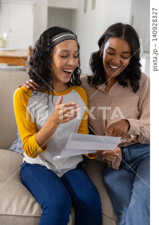 Woman explaining paperwork as teenage daughter reacting on sofa at home Woman explaining paperwork as teenage daughter reacting on sofa at home 140928327