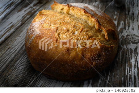 Freshly baked artisanal bread resting on rustic wooden table warm golden crust 140928502