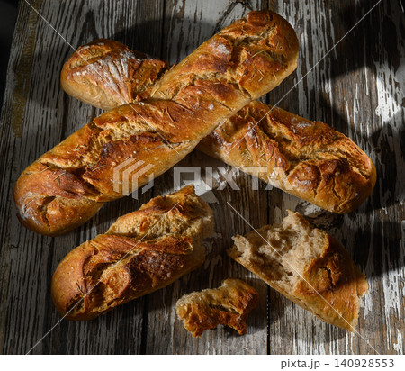 Freshly baked artisan bread arranged beautifully on rustic wooden table in soft Freshly baked artisan bread arranged beautifully on rustic wooden table in soft 140928553