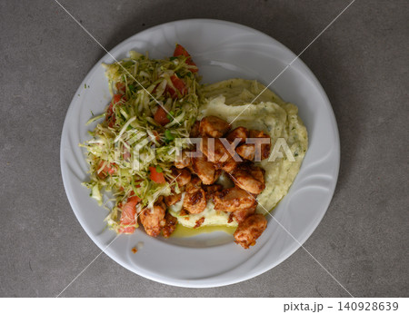 Delicious meal featuring spicy chicken with creamy mashed potatoes and fresh cabbage salad in a cozy dining setting Delicious meal featuring spicy chicken with creamy mashed potatoes and fresh cabbage salad in a cozy dining setting 140928639