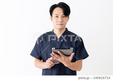 タブレットを持つ紺色のスクラブを着たミドル男性医師 タブレットを持つ紺色のスクラブを着たミドル男性医師 140928714