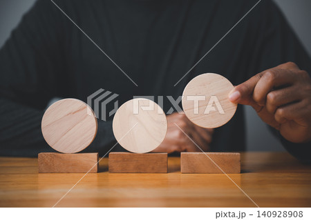 Closeup of a man hand in a pose showing a meaningful sign and gesture for a business concept, placing a wooden circle as a sign for planning strategy and development Closeup of a man hand in a pose showing a meaningful sign and gesture for a business concept, placing a wooden circle as a sign for planning strategy and development 140928908