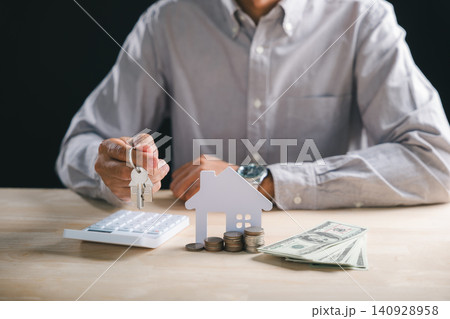 Man holding house keys for real estate property, mortgage loan investment buy home, diligently calculating financial planning with money and calculator to secure property ownership 140928958