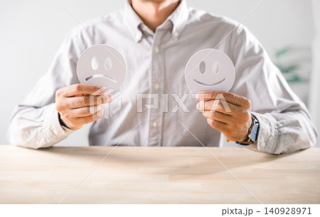 Man shows emotional contrast holding happy sad face signs representing customer satisfaction Mood face options illustrate unhappy or positive emotions impacting service survey feedback for business Man shows emotional contrast holding happy sad face signs representing customer satisfaction Mood face options illustrate unhappy or positive emotions impacting service survey feedback for business 140928971