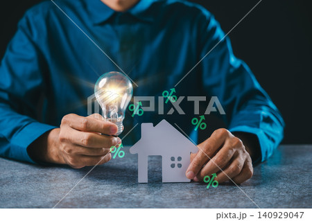 Creative real estate innovation idea shows house light bulb energy savings, businessman holds glowing lightbulb near paper home model for mortgage property interest rate growth Creative real estate innovation idea shows house light bulb energy savings, businessman holds glowing lightbulb near paper home model for mortgage property interest rate growth 140929047