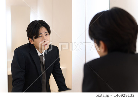 トイレの鏡で表情のチェックをするアジア人男性 トイレの鏡で表情のチェックをするアジア人男性 140929132
