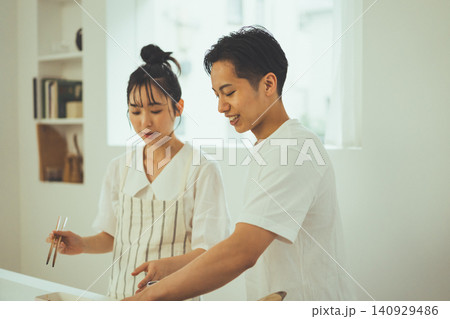 明るいキッチンで笑顔で料理を楽しむカップル 明るいキッチンで笑顔で料理を楽しむカップル 140929486