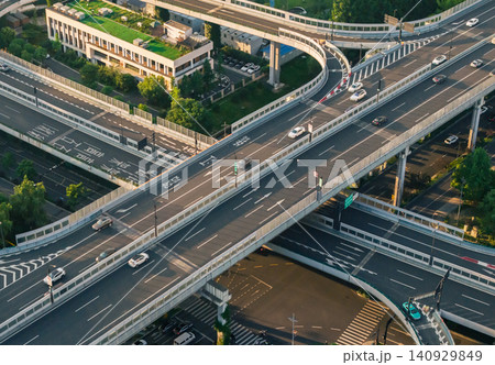 Aerial view captures complex elevated highway structure carrying moving vehicles through a modern urban landscape in China at dusk Aerial view captures complex elevated highway structure carrying moving vehicles through a modern urban landscape in China at dusk 140929849