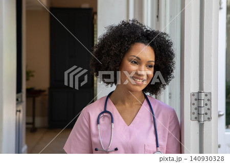 African american woman nurse standing leaning against white clinic doorway and holding stethoscope African american woman nurse standing leaning against white clinic doorway and holding stethoscope 140930328