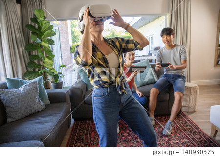 Asian friends adjusting vr headset while holding tablet and smartphone on sofa in living room Asian friends adjusting vr headset while holding tablet and smartphone on sofa in living room 140930375