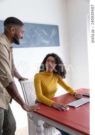 Diverse coworkers collaborating on computer at desk in bright home office using smartphone 140930487