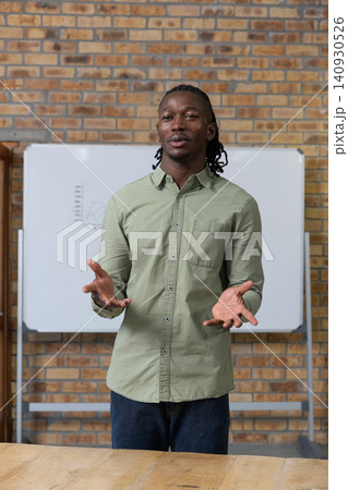 Gesturing african american man presenting line graph on whiteboard behind table in classroom Gesturing african american man presenting line graph on whiteboard behind table in classroom 140930526