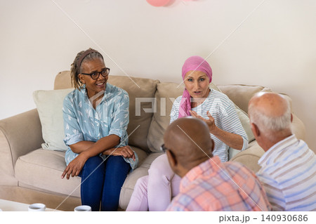 Diverse senior support group members sitting on sofa sharing thoughts with coffee mugs 140930686