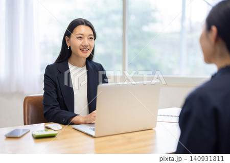 明るい窓辺のデスクでミーティングをする若い日本人のビジネスウーマン 明るい窓辺のデスクでミーティングをする若い日本人のビジネスウーマン 140931811