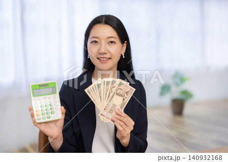 電卓と一万円札を手にカメラ目線で微笑む若い日本人のビジネスウーマン 140932168