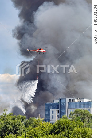 Helicopter fights large fire near commercial building with water drop Helicopter fights large fire near commercial building with water drop 140932204