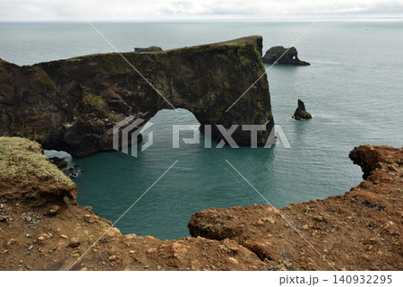 Massive stone arch of Dyrholaey peninsula rising from the sea, Iceland Massive stone arch of Dyrholaey peninsula rising from the sea, Iceland 140932295