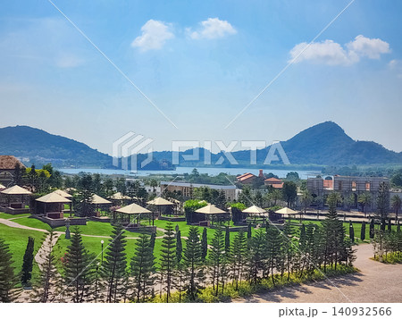 Castello di Bellagio garden grounds with gazebos, pine trees and lake view against tropical hills in Pattaya, Thailand Castello di Bellagio garden grounds with gazebos, pine trees and lake view against tropical hills in Pattaya, Thailand 140932566
