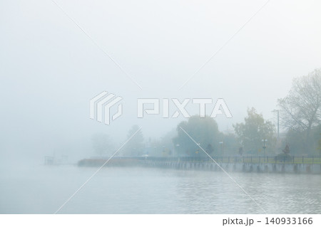 Misty autumn waterfront city district shrouded in atmospheric pollution smoke 140933166