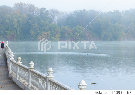 Misty October morning walk along a waterfront promenade beside a calm river Misty October morning walk along a waterfront promenade beside a calm river 140933167