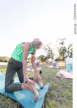Senior woman practicing camel pose in outdoor yoga class Senior woman practicing camel pose in outdoor yoga class 140934094