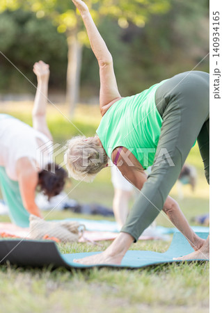 Senior women stretching in a yoga pose on mats in a park 140934165