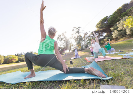 Senior woman practicing yoga outdoors with a group Senior woman practicing yoga outdoors with a group 140934202