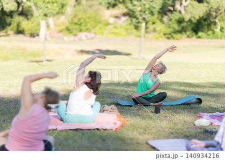 Seniors stretching during outdoor yoga class in park Seniors stretching during outdoor yoga class in park 140934216