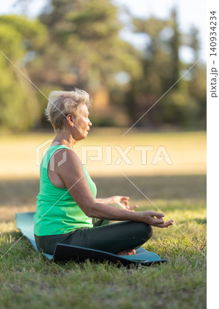 Senior woman practicing yoga lotus pose outdoor Senior woman practicing yoga lotus pose outdoor 140934234