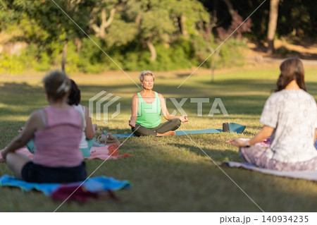Senior women meditating in lotus pose in park Senior women meditating in lotus pose in park 140934235