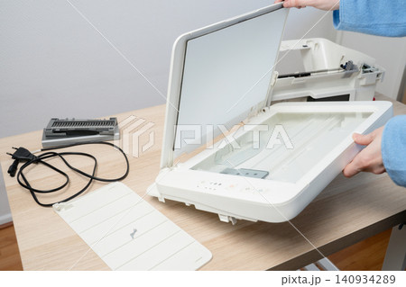 Hands Opening Flatbed Scanner For Printer Repair And Maintenance On Wooden Office Desk 140934289