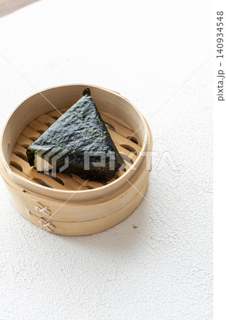 Close-up of traditional Japanese onigiri rice ball served in a natural bamboo bowl 140934548